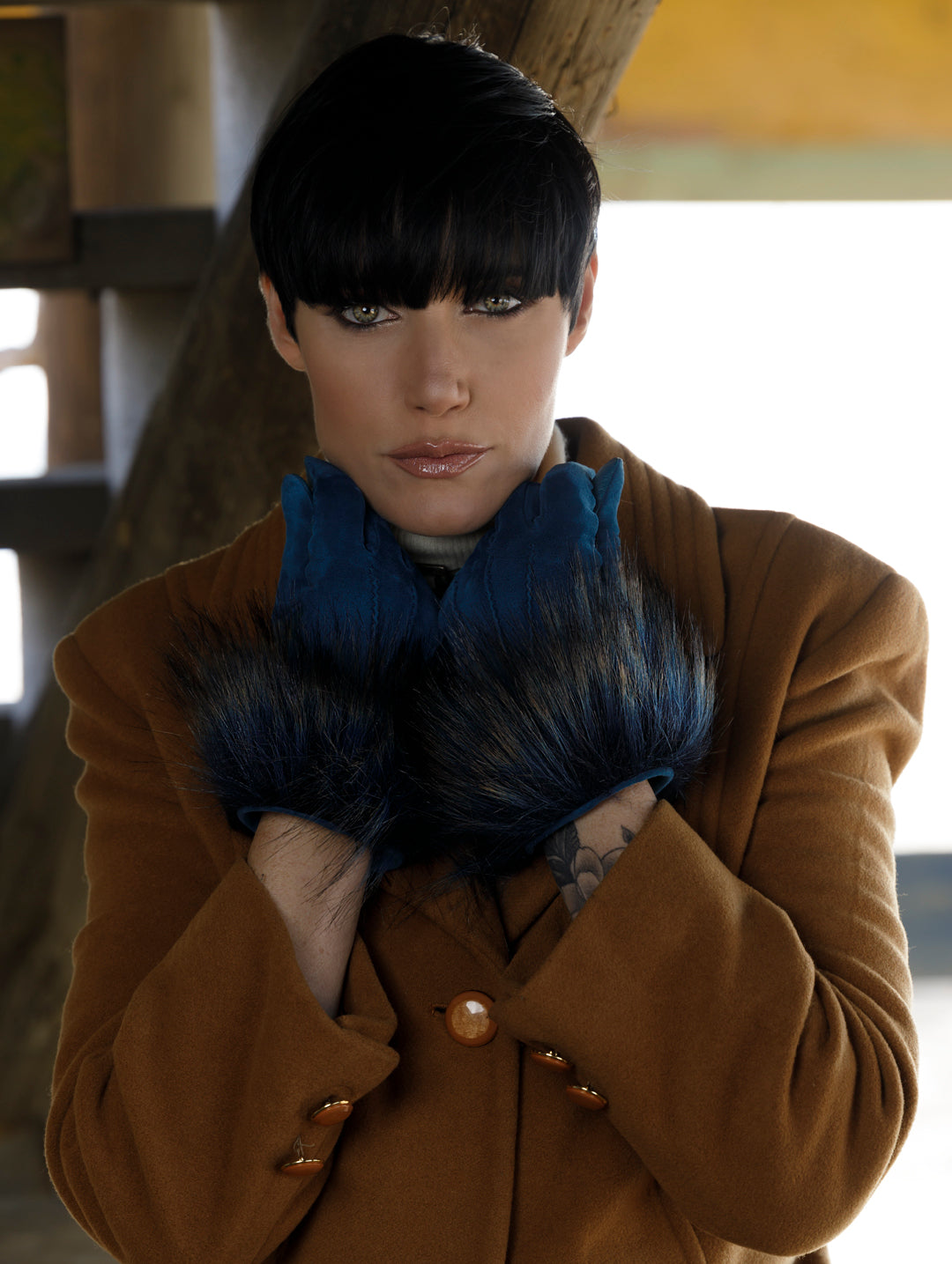 Ladies' short blue nappa gloves with eco fur cuffs, elegantly styled against a warm brown coat, showcasing luxury and craftsmanship.
